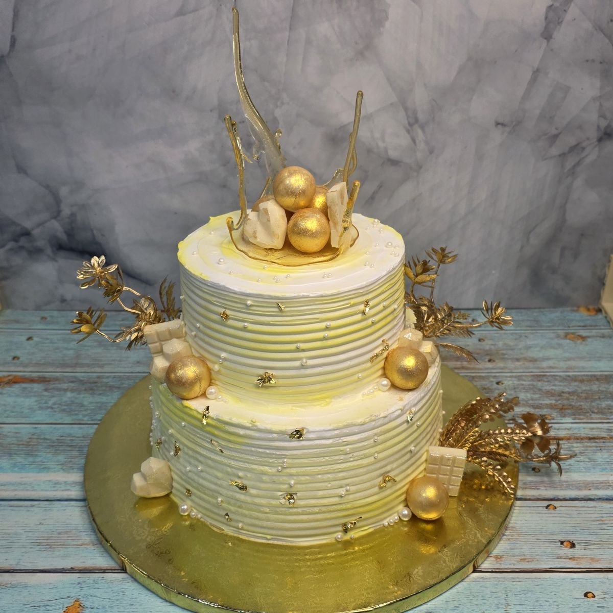 A two-tier white and gold ombre cake with hand-pulled sugar shards and gilded spheres