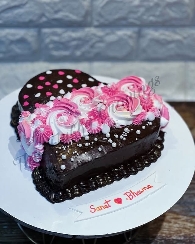 A heart-shaped chocolate cake piped with pink and white rosettes