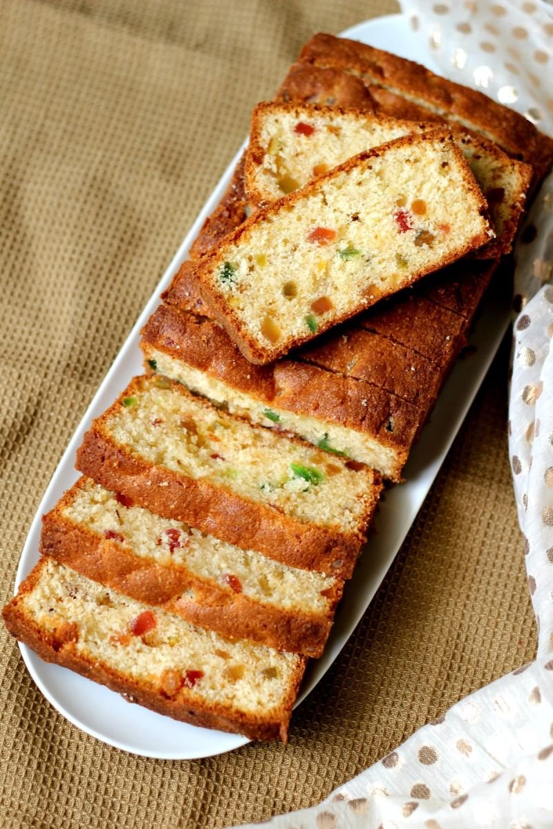 A sliced tutti-frutti tea loaf served on a white platter