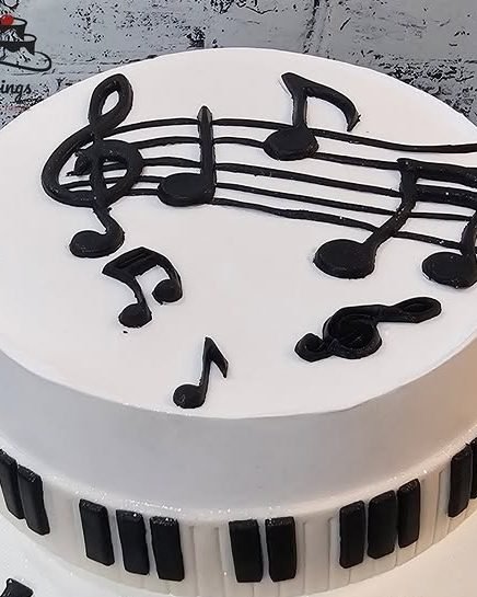 A white cake piped with musical notes above a fondant piano keyboard